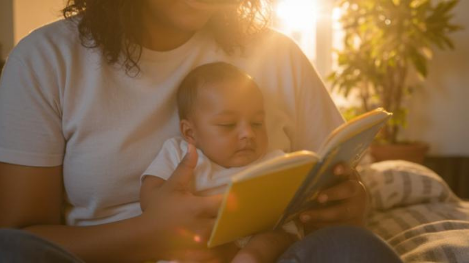 Caregiver holding a newborn and reading a high-contrast board book close to baby’s face
